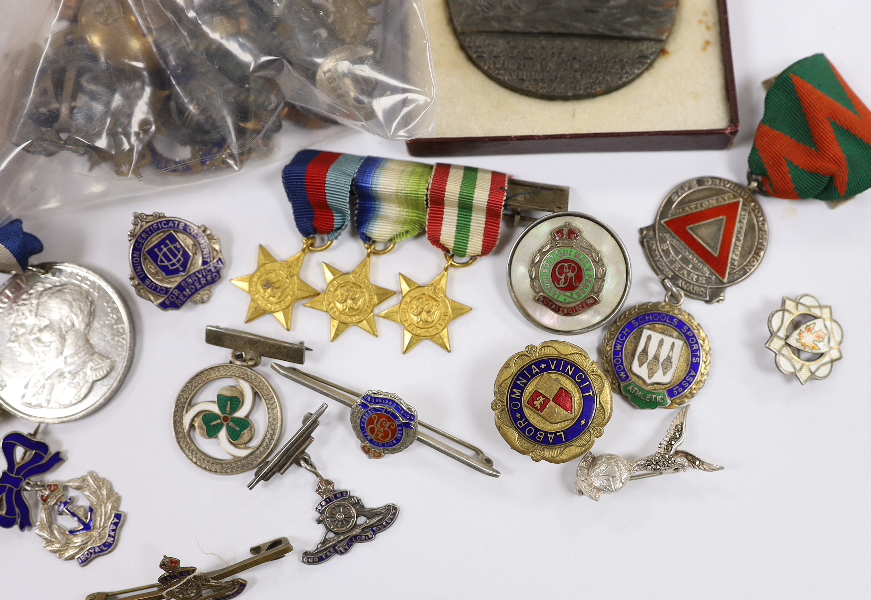 A collection of medals, cap badges, commemorative coins etc. including; a cased RMS Lusitania medal, Royal Artillery sweetheart brooches, a miniature WWII medal group of three stars; the 1939-45 Star, the Atlantic Star a